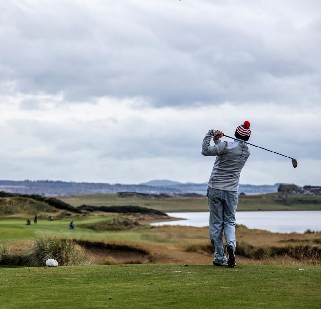 A golfer taking a swing on Castle Stuart golf course