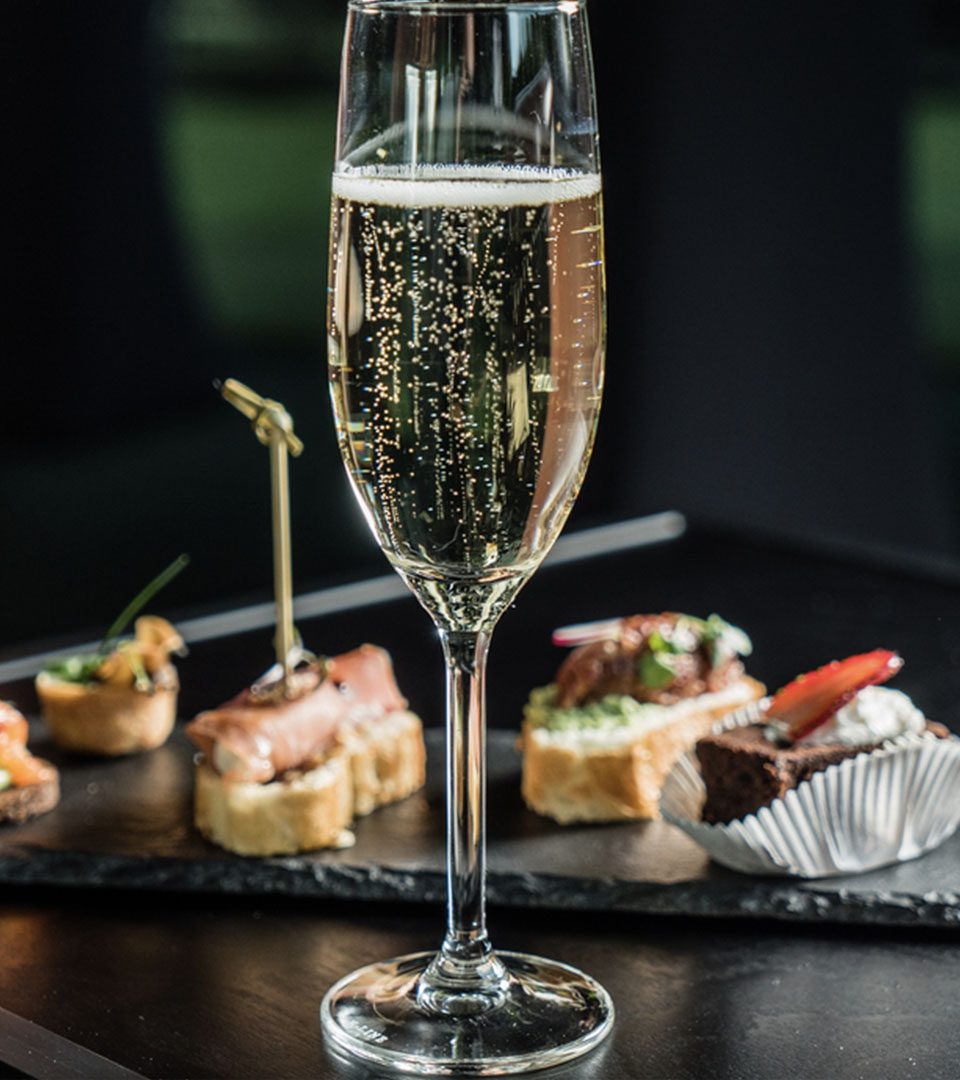 A glass of champagne with canapés on a plate of slate