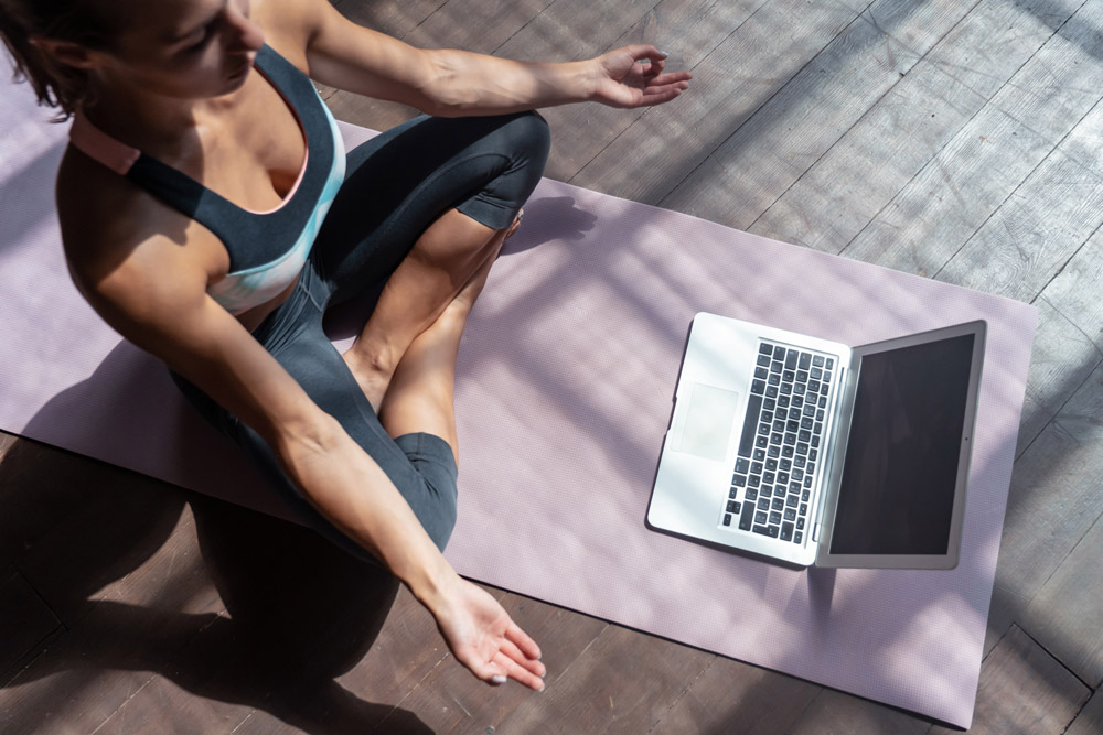 Woman doing yoga in front of a lap top
