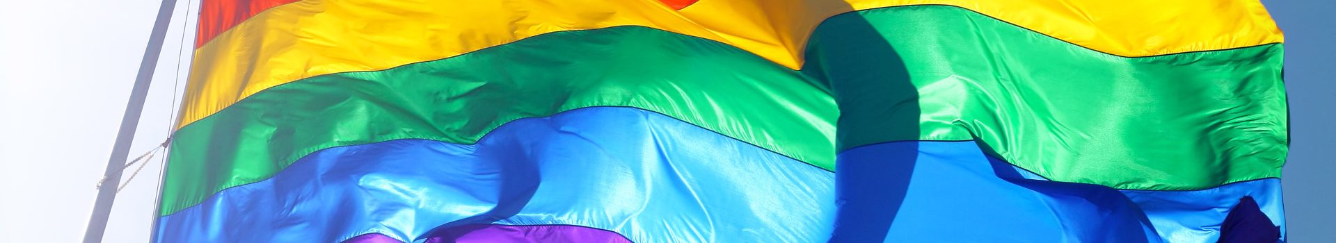 Sunlight shines through a Pride rainbow flag