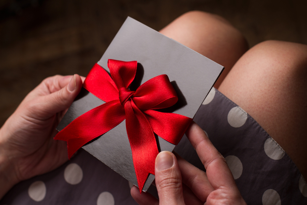 Woman holding a gift voucher wrapped in a red ribbon