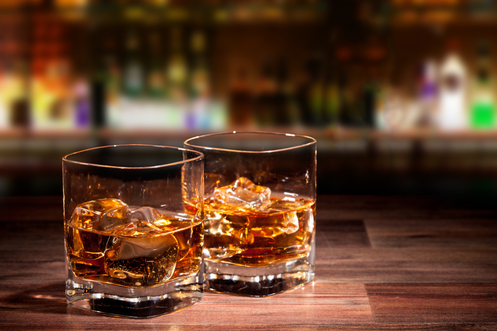 Two whisky glasses on a bar top