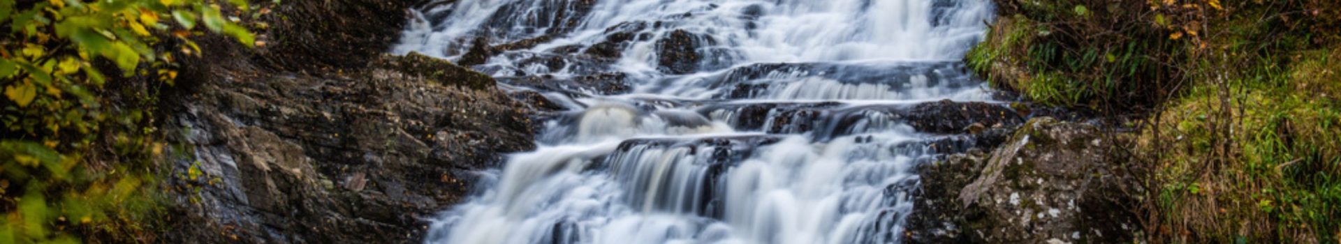 Small waterfalls on the Allt na Bodachan burn above the main drop at Plodda Falls in Glen Affric with the autumn colours in the trees.