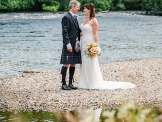 A new bride and groom pose for wedding photos on the banks of River Ness.