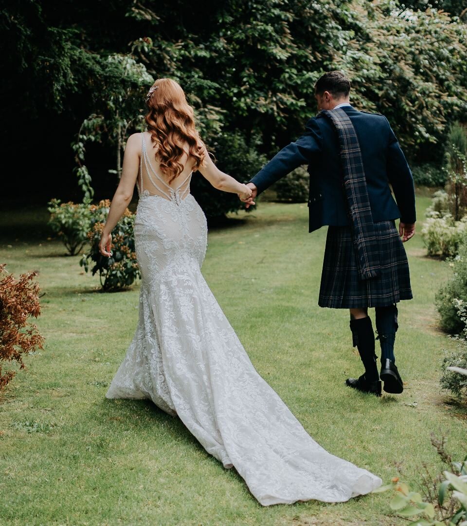 A Scottish wedding photo with our bride and groom walking in the Ness Walk Hotel Gardens in Autumn.