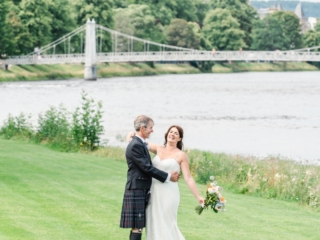 A new bride and groom pose for wedding photos on the banks of River Ness.