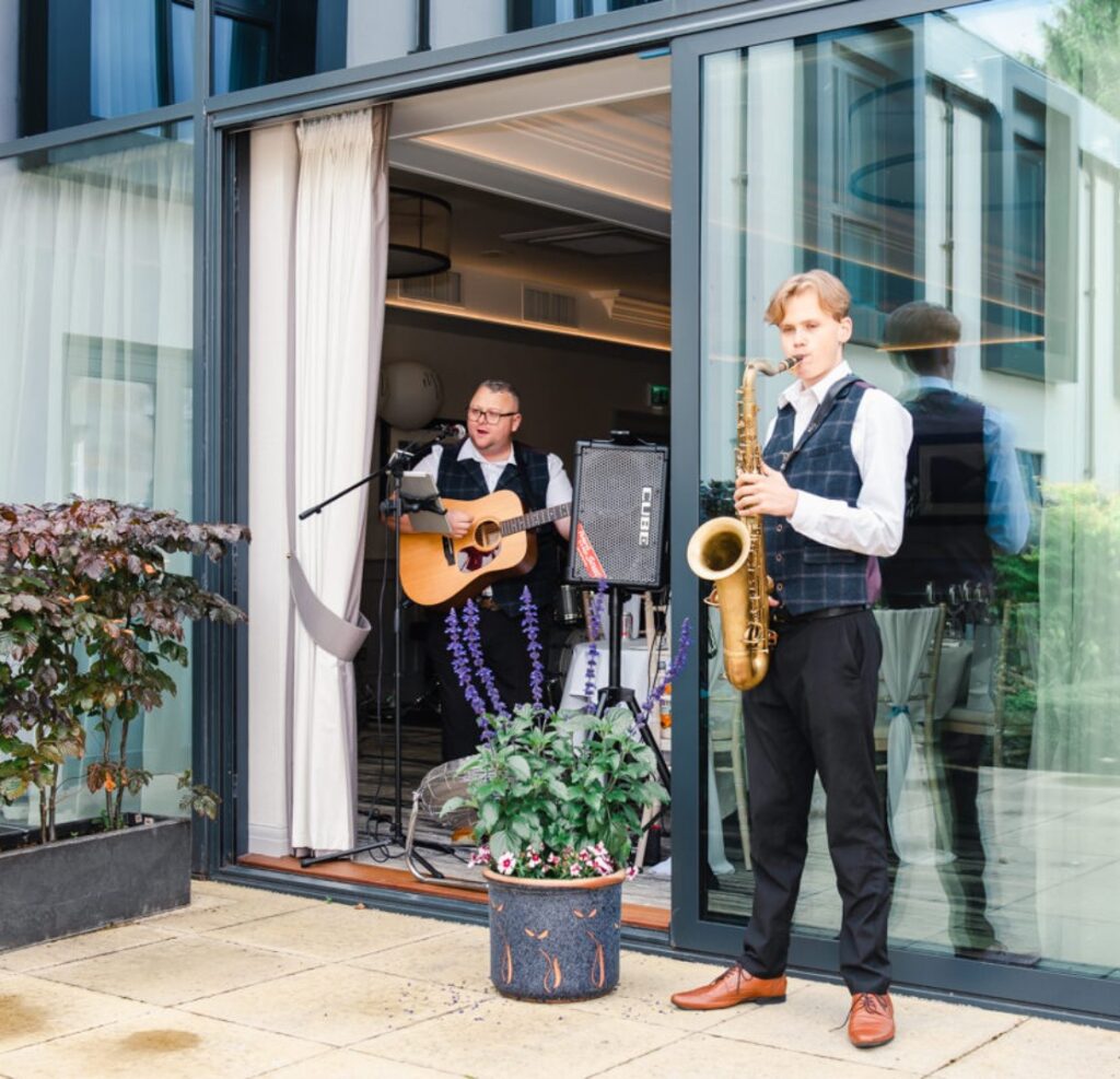 Wedding entertainers play music to Scottish wedding guests on the garden terrace at Ness Walk Hotel.