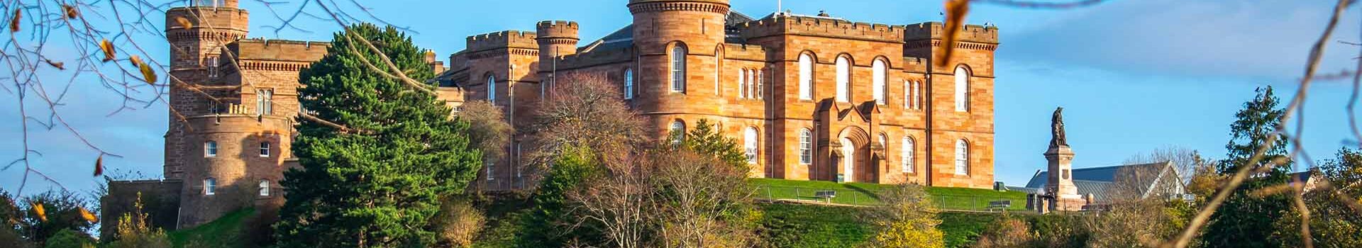 Inverness Castle with a blue sky background and trees at the front.
