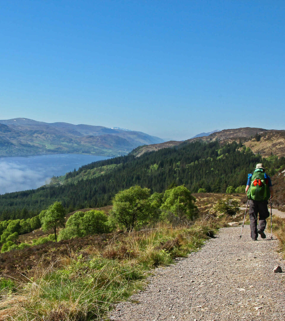 Hiker on the Great Glen Way in Scotland, with Scottish Highlands and loch in the distance