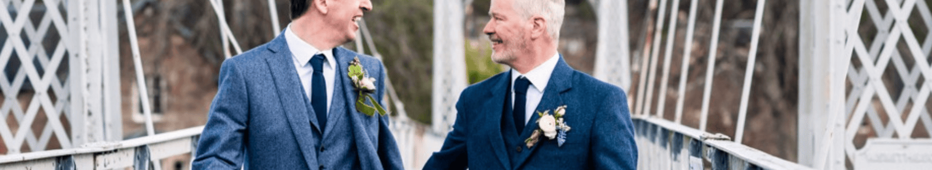 Same sex wedding couple holding hands crossing bridge over River Ness on way to wedding at Ness Walk