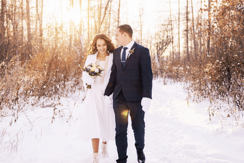 A couple walk in the snow on their wedding day.