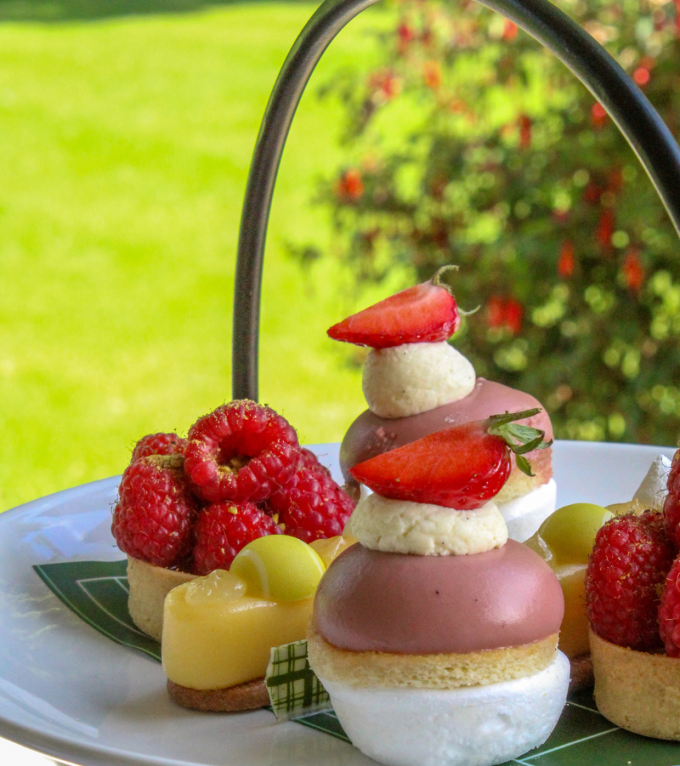 Selection of Wimbledon-themed afternoon tea desserts at Ness Walk, including strawberry-topped mousse cakes, fresh raspberry tartlets, and lemon pastries served on a tiered afternoon tea stand.